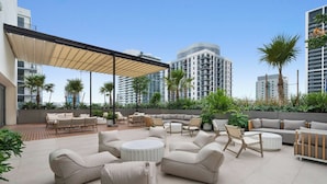 A rooftop patio with outdoor furniture, palm trees, and modern buildings in the background. - Sky Sanctuary With Rooftop Pool & Hot tub (Miami)