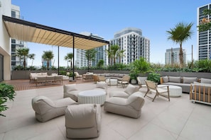 A rooftop patio with outdoor furniture, palm trees, and modern buildings in the background. - Sky Sanctuary With Rooftop Pool & Hot tub (Miami)