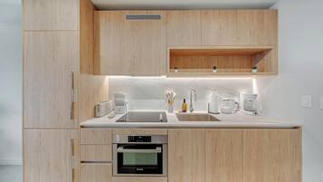 A modern kitchen with wooden cabinets, a built-in oven, a sink, and a coffee maker.