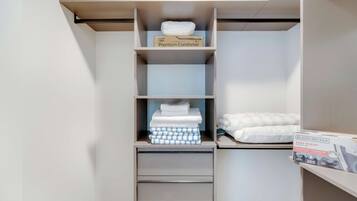 A closet with shelves and drawers, containing folded towels and a box labeled "Premium Comforter."