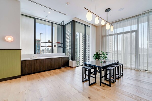 Una cocina moderna con un gran ventanal, suelo de madera y un comedor con mesa y sillas.