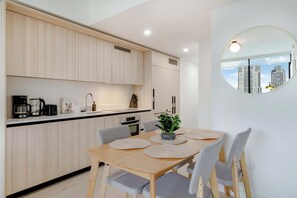 A modern kitchen with wooden cabinets, a dining table with chairs, and a round mirror on the wall. - City Atelier Downtown, Sauna, Pool, Parking (Miami)