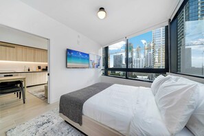 A modern bedroom with a large bed, a desk, and a view of a cityscape through large windows. - Downtown Edit Resort Style Stay With Lux Amenities (Miami)