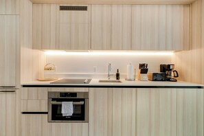 A modern kitchen with wooden cabinets, a built-in oven, a sink, and a coffee maker. - Downtown Edit Resort Style Stay With Lux Amenities (Miami)