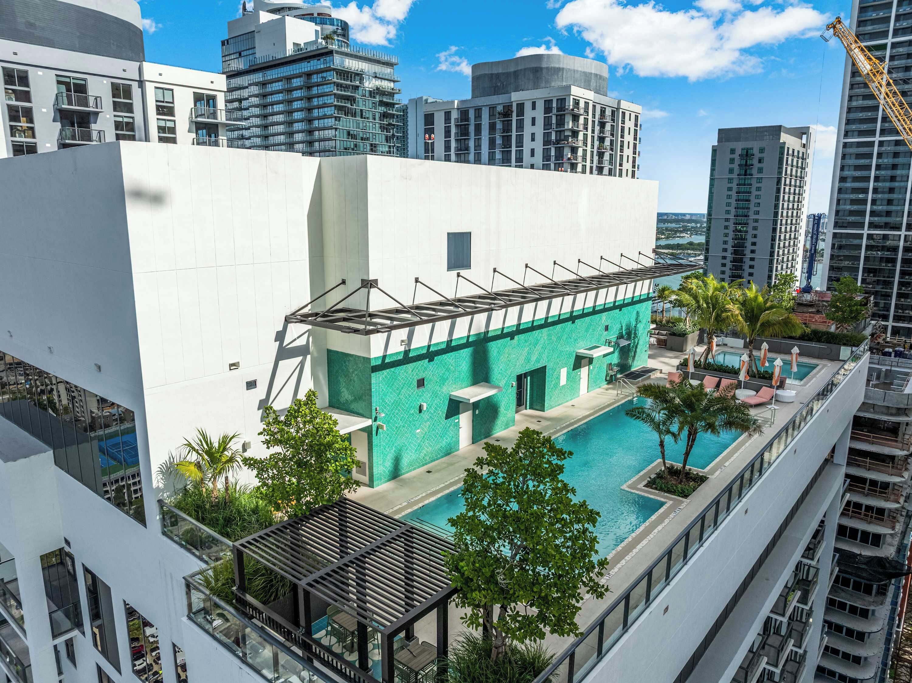 A modern building with a rooftop pool, surrounded by high-rise buildings.