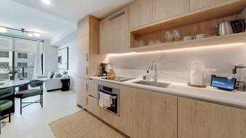 Une cuisine moderne avec des meubles en bois, un four encastré, un évier et un écran numérique.