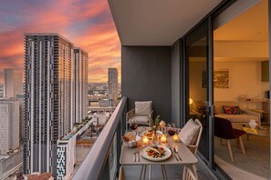 A balcony with a dining table set for two, overlooking a cityscape at sunset. - Rumrunner, Downtown, Pool, Gym, Full Service Tower (Miami)