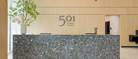 En receptionsdisk med en marmorskiva, en krukväxt och en skylt med texten ”501 First Residences”.