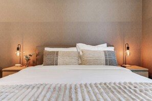 A neatly made bed with a textured blanket, two bedside tables with lamps, and a wall-mounted light fixture. - Aura Studio, Heart of Miami With Resort Amenities (Miami)