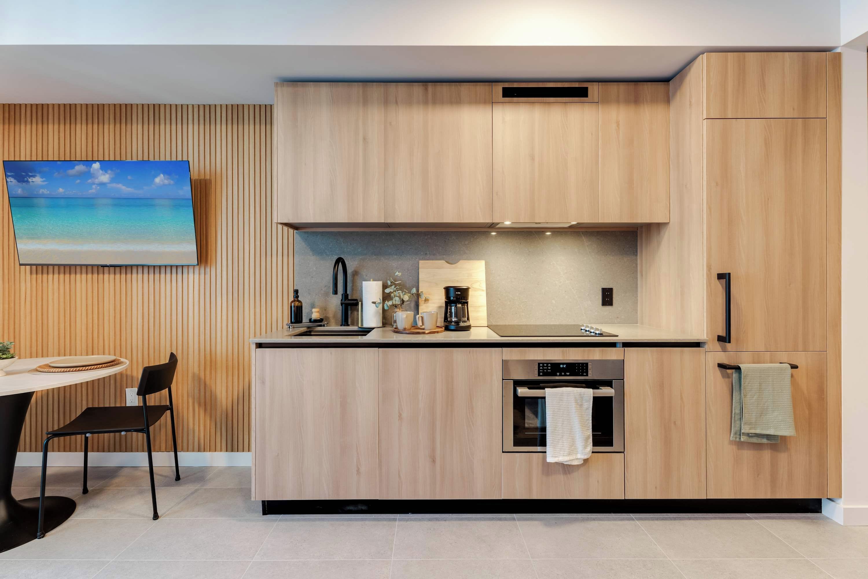 Eine moderne Küche mit Holzausstattung, einem eingebauten Backofen und einem Essbereich mit Tisch und Stühlen.
