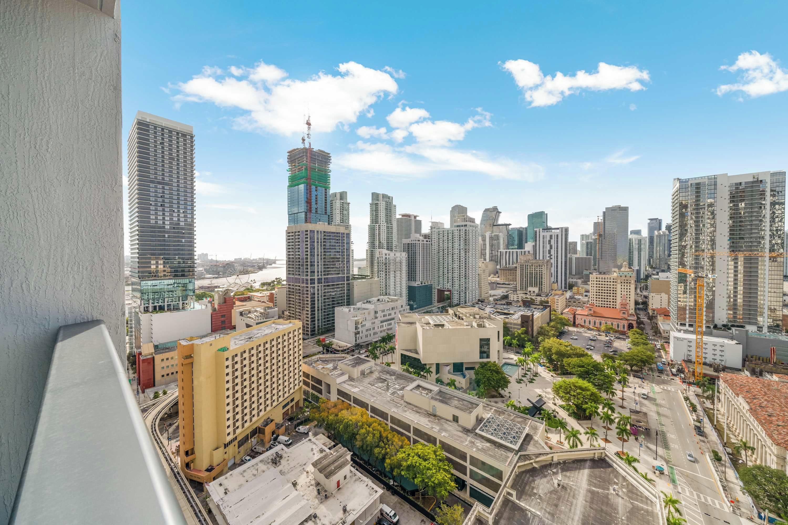 Panorama urbano con grattacieli, cielo sereno e strada trafficata.
