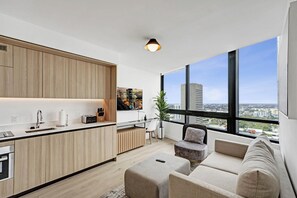 Eine moderne Wohnung mit Küche, Essbereich und Sitzgelegenheiten an großen Fenstern.