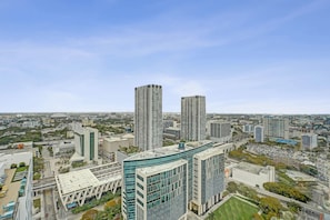 Ein Hochhaus mit moderner Glasfassade, umgeben von weiteren Hochhäusern und blauem Himmel.