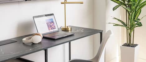 A modern workspace with a laptop, headphones, and a plant.
