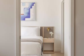 A bedroom with a bed, a nightstand, a wall-mounted light, and a piece of abstract art. - City Dreams Sauna, Rooftop Pool & Parking (Miami)