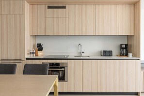 A modern kitchen with wooden cabinets, a stainless steel sink, a toaster, and a coffee maker. - City Dreams Sauna, Rooftop Pool & Parking (Miami)