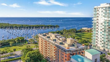 A high-rise hotel with multiple balconies, a swimming pool, and a view of the marina with boats.