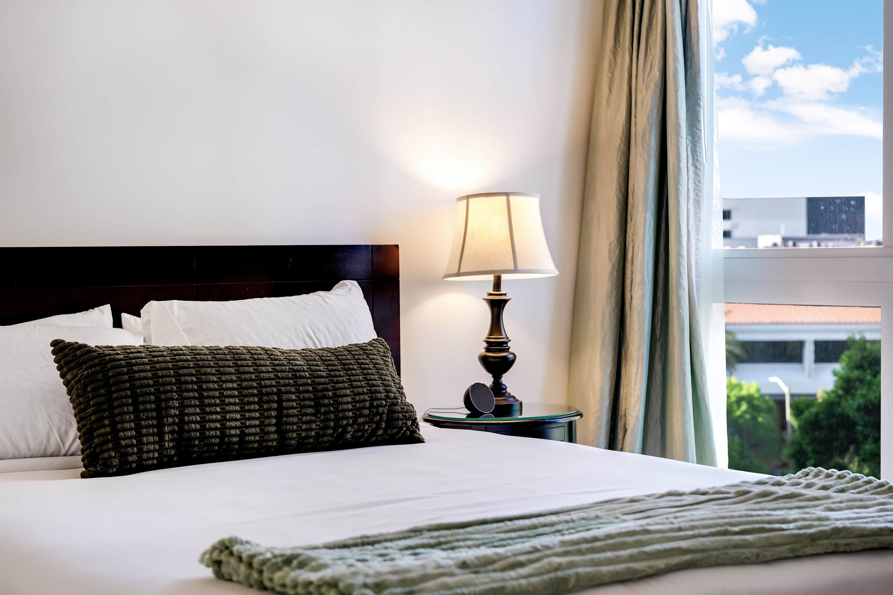 Une chambre d’hôtel avec un lit, une lampe et une vue sur l’extérieur.