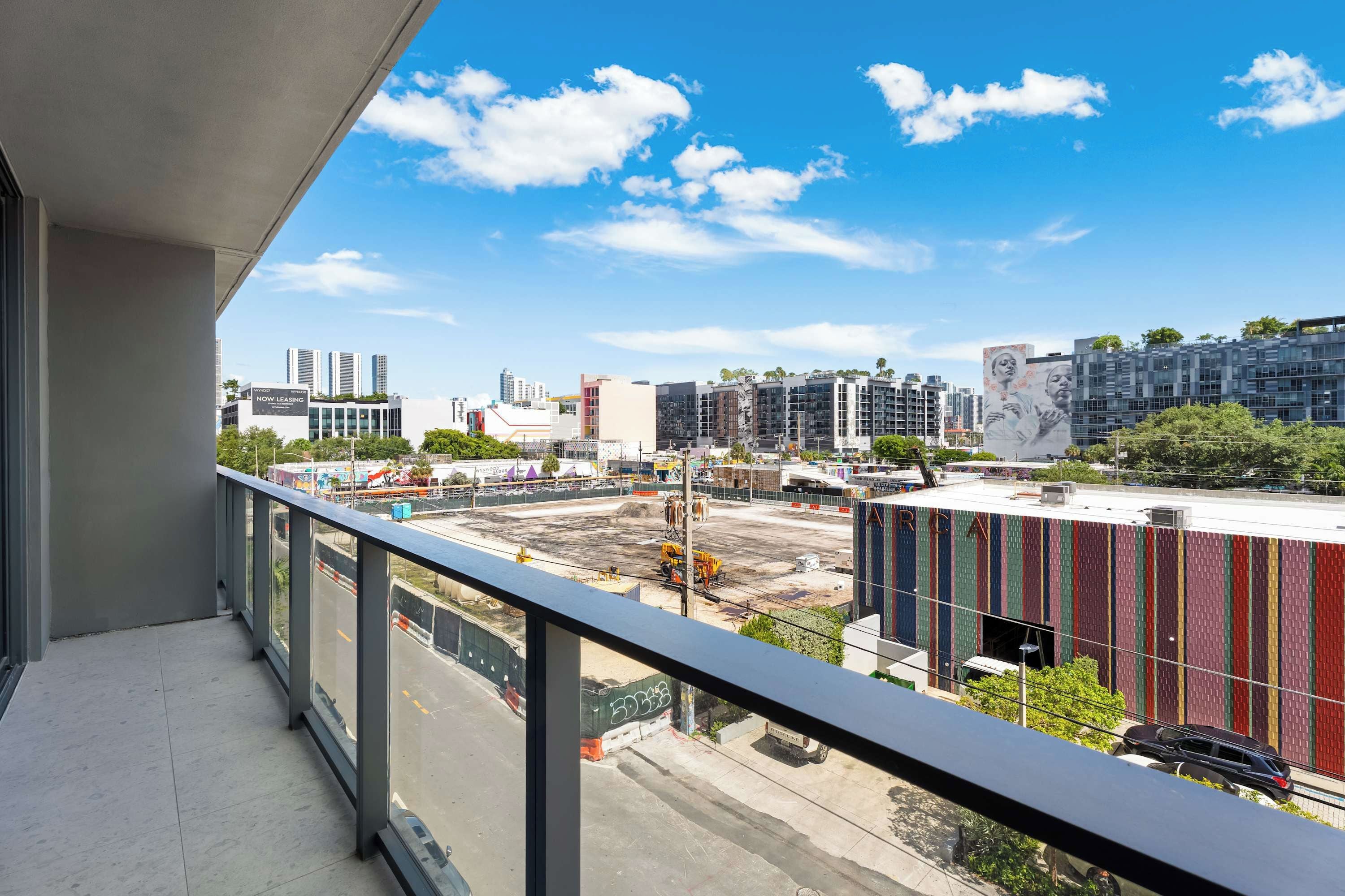 Un balcón con vistas a un paisaje urbano, que incluye edificios modernos y una obra en construcción.