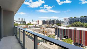 Un balcón con vistas a un paisaje urbano, que incluye edificios modernos y una obra en construcción.