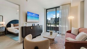 A modern hotel room with a bed, a sofa, a coffee table, a TV, and a city view through the window. - Wynwood Pad- Stylish Apt With View & Rooftop Pool (Miami)