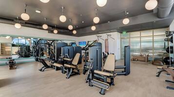 Ein Fitnessstudio mit Trainingsgeräten, großen Fenstern und Blick auf die Stadt.