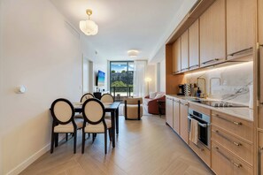 A modern kitchen with wooden cabinets, a marble countertop, and a dining area with a table and chairs. - Wynwood Pad- Stylish Apt With View & Rooftop Pool (Miami)