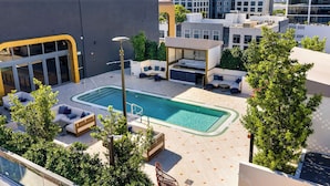 A rooftop pool area with lounge seating, a covered seating area, and a view of surrounding buildings. - Wynwood Pad- Stylish Apt With View & Rooftop Pool (Miami)