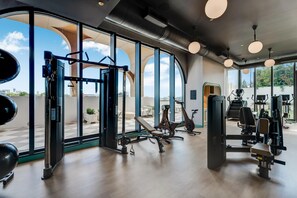 A gym with exercise equipment, large windows, and a view of the city. - Wynwood Pad- Stylish Apt With View & Rooftop Pool (Miami)