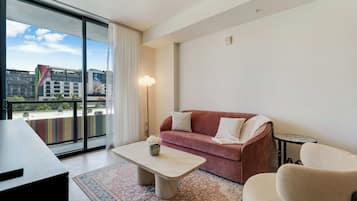 Ein modernes Wohnzimmer mit Sofa, Sessel, Couchtisch und Blick auf Gebäude durch große Fenster.