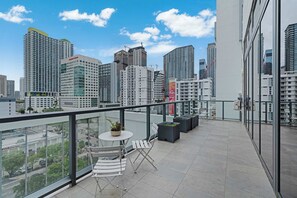 Terraço no terraço com vista para a cidade, uma mesa com cadeiras e plantas em vasos.