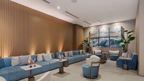A modern hotel lobby with a blue sofa, a round table, and a large painting on the wall. - Brickell Skyline- Pool, Gym, and Central Location (Miami)