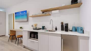 Uma cozinha moderna com armários brancos, micro-ondas embutido, pia e máquina de café.