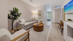 A modern living room with a sofa, a round coffee table, a plant, and a painting on the wall. - Brickell Skyline- Pool, Gym, and Central Location (Miami)