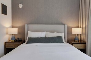 A hotel room with a large bed, two bedside tables with lamps, a wall-mounted light, and a plain wall. - Brickell Skyline Pool, Gym, and Central Location (Miami)