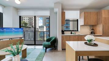A modern apartment with a dining area, kitchen, and a balcony with a view of buildings.