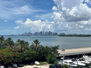 A marina with boats docked, a city skyline in the background, and a clear sky. - Bahia Serena - Bay Views on Marina With Parking (North Bay Village)