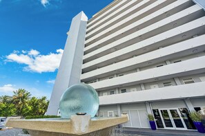 A modern building with a prominent vertical structure and a water feature in the foreground. - Bahia Serena - Bay Views on Marina With Parking (North Bay Village)