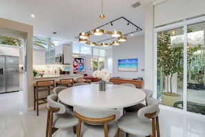A modern kitchen with a central island, stainless steel appliances, and a dining area with a round table and chairs. - Casa Anton Artist Home, Pool & Rooftop Terrace (Miami)