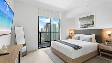 Habitación de hotel moderna con una cama grande, un escritorio, una silla y vistas a la ciudad desde el balcón.