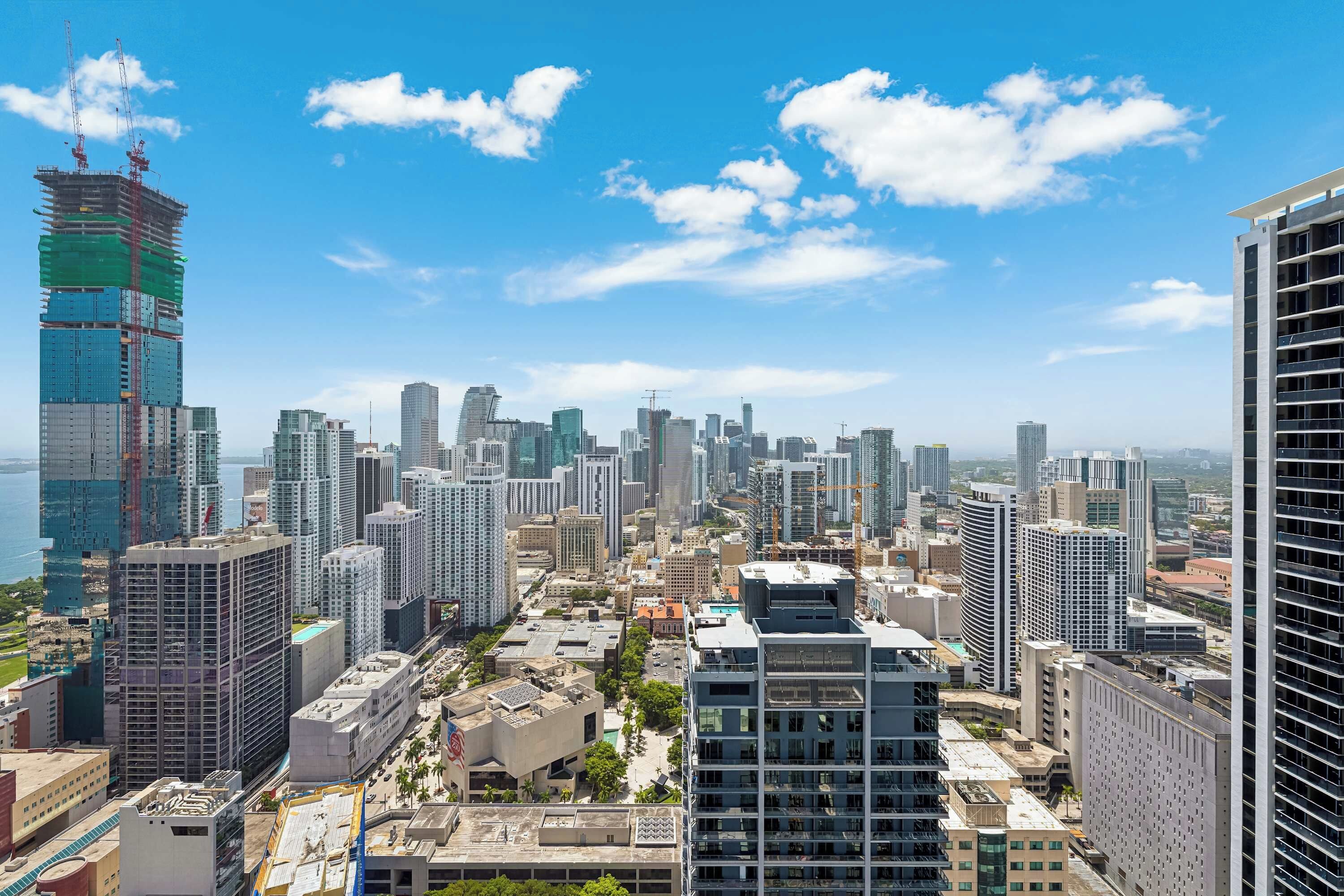 A cityscape with high-rise buildings, some under construction, and a clear sky.