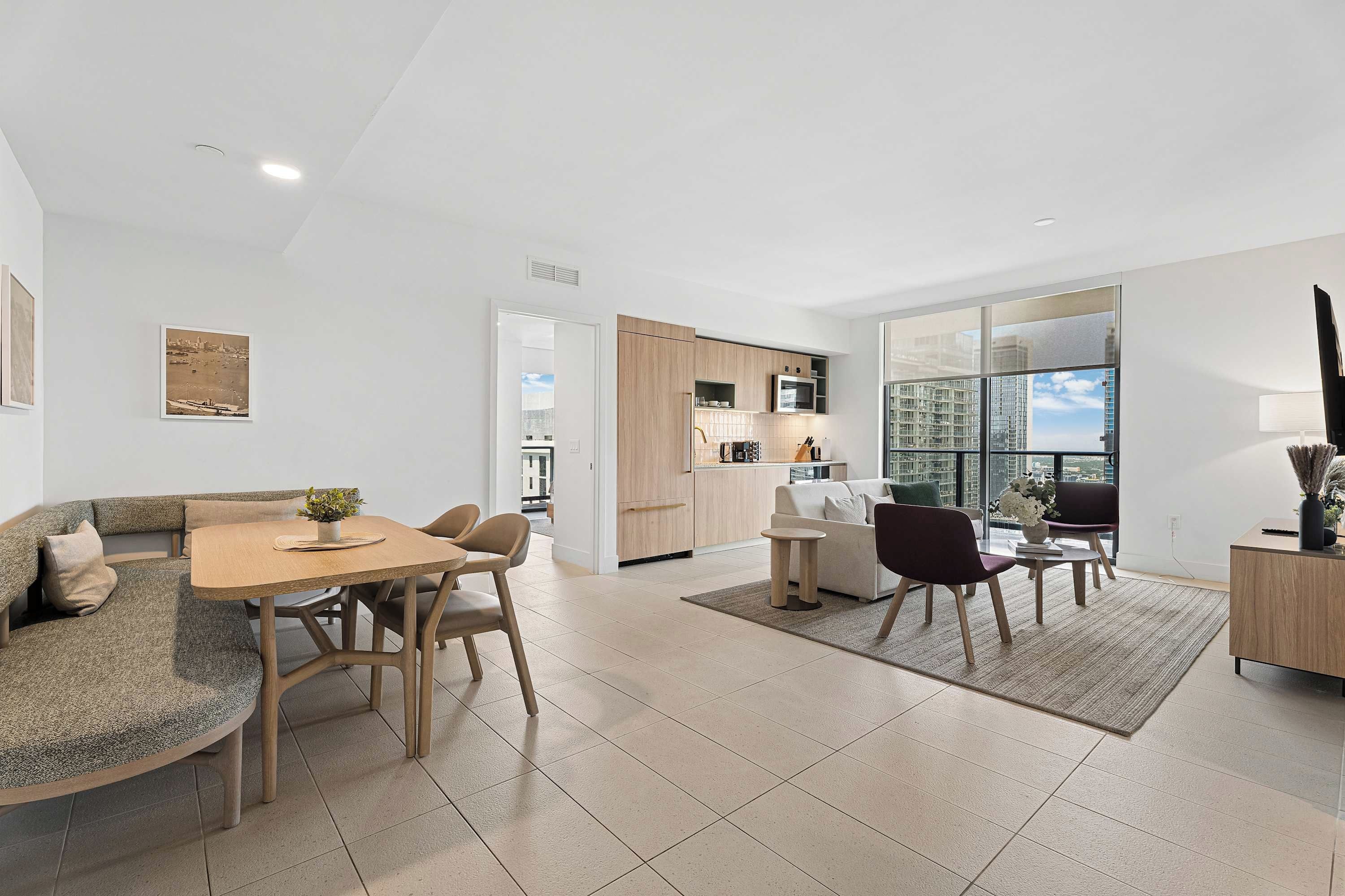 A modern living space with a dining area, kitchen, and seating area with a view.