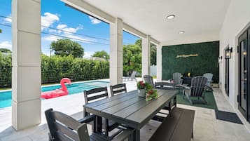 A covered outdoor area with a pool, seating, and a green wall with a quote.