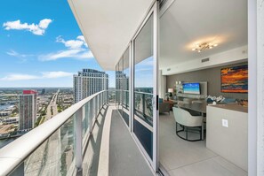 Ein Balkon mit Blick auf die Stadt, ein Essbereich, ein Fernseher und ein Gemälde.
