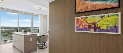 Un intérieur moderne comprenant un coin repas, un îlot de cuisine et une grande fenêtre donnant sur la ville.