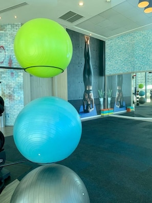 Ein Fitnessraum mit Trainingsbällen, einer Yogawand und einer Ziegelwand.