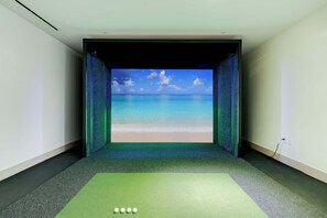 A room with a large screen displaying a beach scene, a green exercise mat, and a power outlet on the wall. - Sky Corner Residence Pool, Parking, Amenities (Miami)