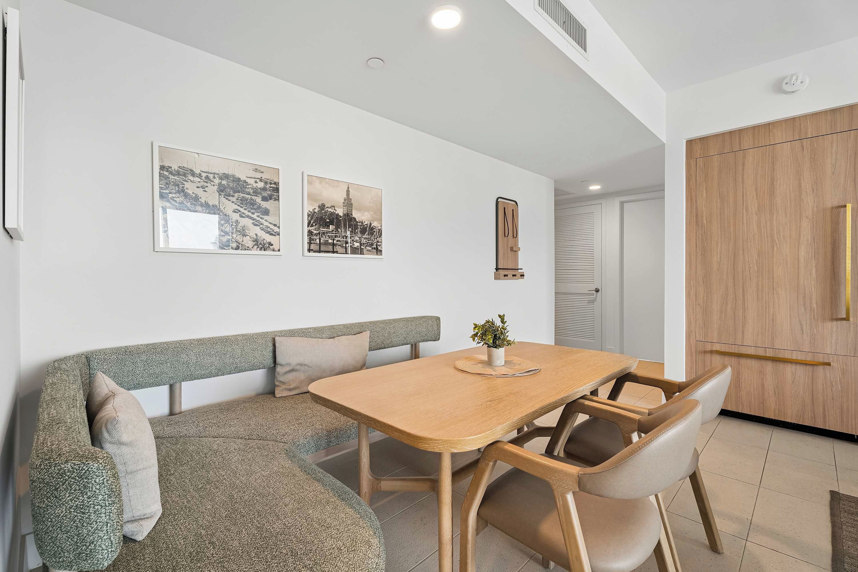 A dining area with a wooden table and chairs, a bench, and two wall-mounted pictures.