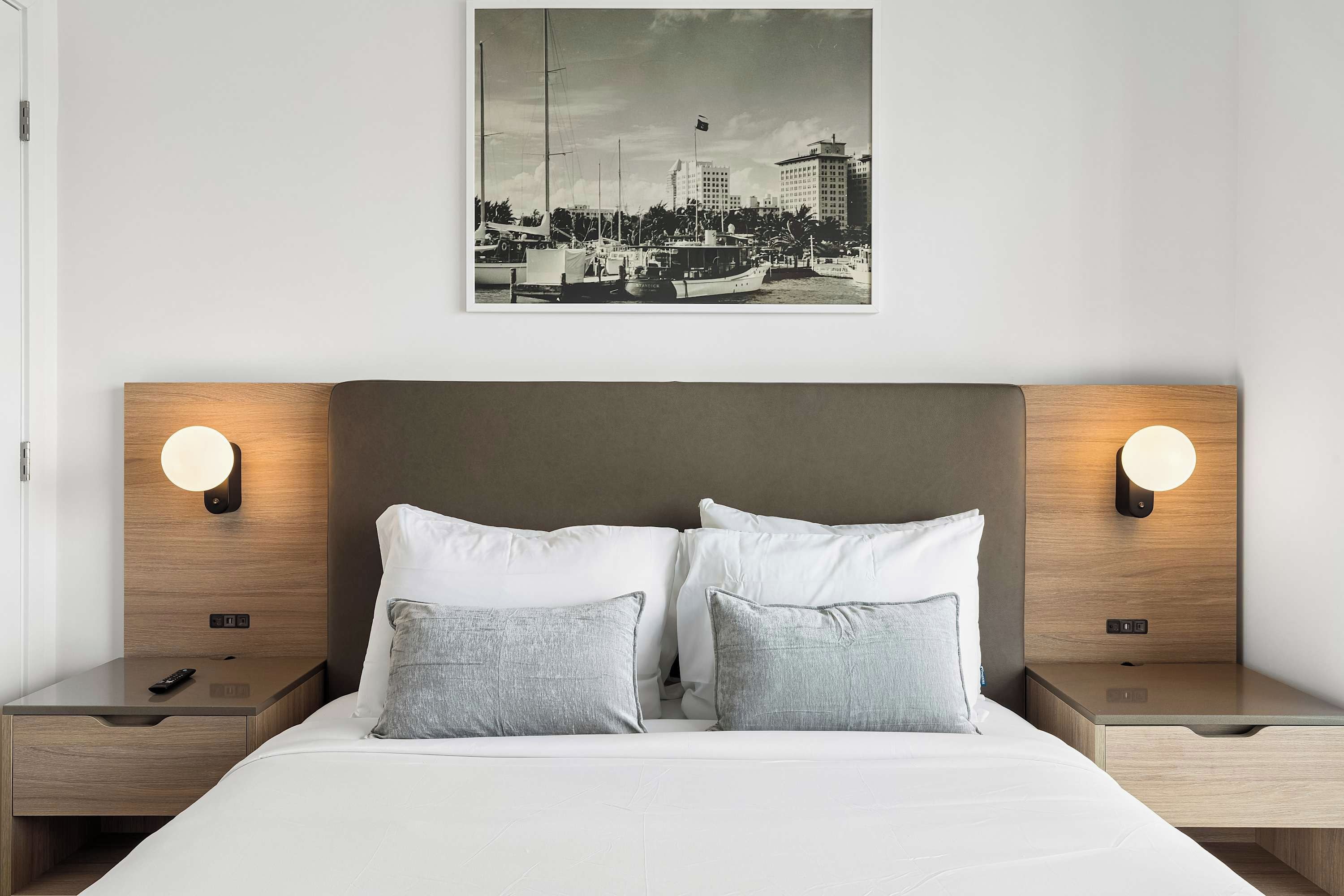 Een hotelkamer met een bed, twee nachtkastjes, een wandlamp en een aan de muur bevestigd schilderij.