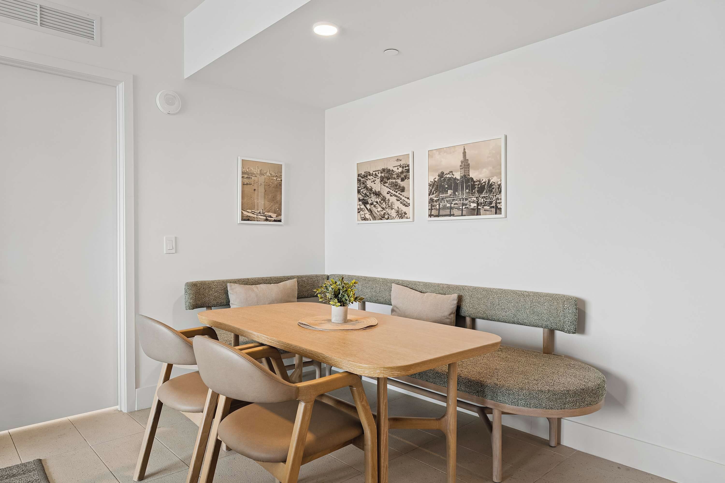 A dining area with a wooden table, cushioned chairs, and a bench with a patterned backrest.